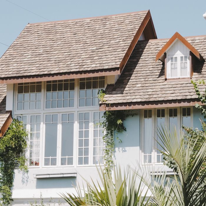 Elegant suburban house with large windows and a shingled slate roof in sunlight.